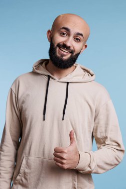 Memnuniyet portresi gösteren işaret veren mutlu Arap adam. Yüzünde gülümseme olan neşeli Arap modeli kameraya bakarken kabullenme ve uzlaşma hareketi yapıyor.