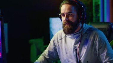 Takım arkadaşlarıyla konuşan neşeli bir oyuncu rekabetçi esport turnuvası oynarken galibiyeti kutluyor. Mutlu adam arkadaşlarıyla çok oyunculu video oyunlarını seviyor, kazandıktan sonra heyecanlanıyor.