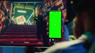 Yeşil ekrandaki favori içerik yaratıcısını izleyen adam şu anda oynadığı oyunun ipuçlarını gösteriyor, kapatın. İnternette ilham arayan oyuncu Chroma Key Phone 'da, görevine takılıp kalmış.