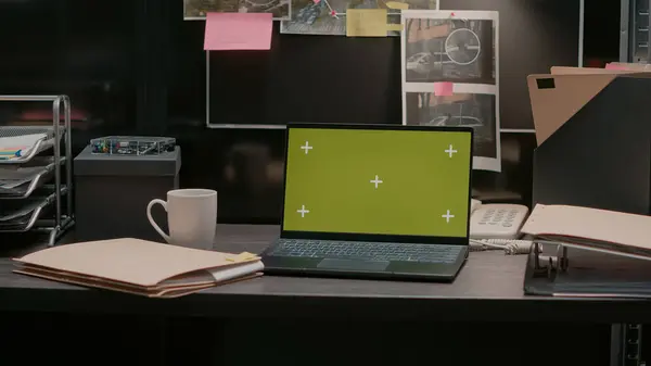 Modern laptop with greenscreen placed on archive desk in police evidence room, blank mockup template on pc. Wireless computer showing isolated chroma key copyspace, incident room.