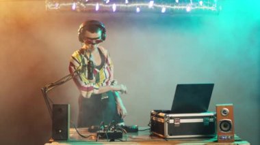 DJ şarkıcısı kontrol düğmelerinde tekno müzik yaratıyor, çılgın bir makyaj yapıyor ve müzik seti ekipmanlarıyla karıştırıyor. Gece kulübü partisi için pikaplarda disko çalan sanatçı. Üçayak atışı.