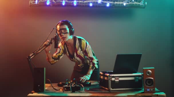 ディスクジョッキーアーティストはマイクで叫び ナイトクラブで現代のテクノパーティーでファンキーな雰囲気を作り出します 新しいレコード ステレオ機器をミックスするためにターンテーブルを使用する女性Dj トリポッドショット — ストック動画