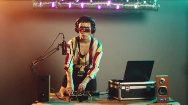 DJ sunar, sahnede sembolü bilmiyorum, cevaptan habersiz ve kararsız davranıyor. Genç sanatçı karışık melodiler ve omuz silkme konusunda kafası karışık ve kararsız. Üçayak atışı.