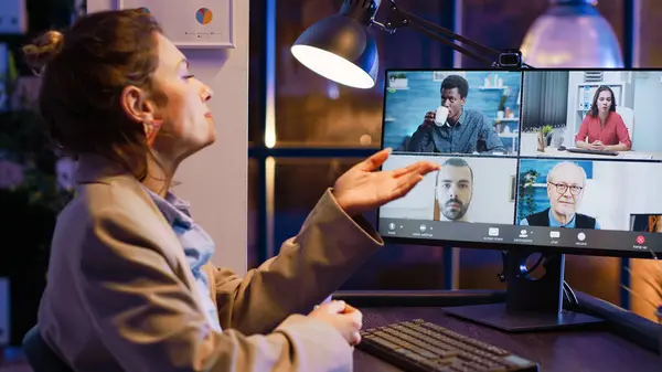 Entrepreneur attending business meeting on video call talking to colleagues about startup investment. Employee using online conference chat late at night, chatting on videoconference.