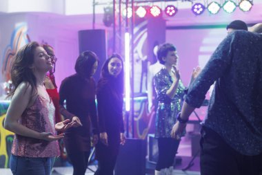 Gece kulübündeki disko partisinde dans eden ve rahatlatan enerjik genç bir kadın. Kalabalık bir kulüpte dans pistinde gece hayatının tadını çıkarırken kız müzik ritmine ayak uyduruyor.