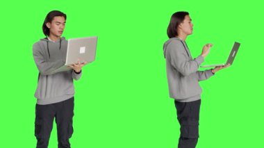 Genç adam video konferansında insanları laptopla karşılıyor, online konferans üzerinden insanlarla iletişim kuruyor. Yeşil ekrana karşı Asyalı adam telekonferansta arkadaşlarıyla bilgisayar başında sohbet ediyor..
