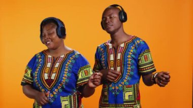 Kamerada hayali gitar çalıyormuş gibi yapan, kulaklıkla müzik dinleyen ve stüdyoda müzik aleti çalan etnik bir çift. Afrikalı erkek ve kadın şarkıları seviyor.