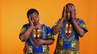 Hasta etnik insanlar kamerada, migren ve gerilimden muzdarip eğlenceli belirtiler gösteriyorlar. Afrikalı evli çift, baskıyı azaltmak ve kameradaki baş ağrısından kurtulmak için tapınakları ovalıyor..