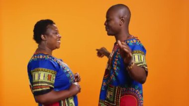 Afrikalı Amerikalı partnerler stüdyoda dans ederken, en sevdikleri şarkının tadını çıkarırken ve romantik slow dans hareketleri gösterirken eğleniyorlar. Etnik evli çift turuncu arka planda havalı şarkılar dinliyor..