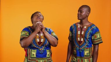 Afro-Amerikalı çift taze kahvenin tadını çıkarıyor, kadın elinde kağıt bardak tutuyor ve sıcak içecekten kafein kokusu alıyor. Etnik insanlar stüdyodaki enerji içeceği kokusuna bayılıyorlar..