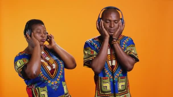 非洲裔美国人无忧无虑的伴侣一边听着歌曲 一边在摄像机上放声大哭 快乐的丈夫和妻子用时髦的曲调跳舞 用耳机欣赏音乐 — 图库视频影像