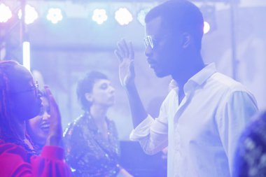 Dans eden erkek ve kadın, sahne ışıklarıyla aydınlatılmış dans pistinde el ele tutuşuyorlar. Genç Afro-Amerikan dansçılar karanlık gece kulübünde gece hayatının tadını çıkarıyorlar.