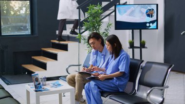 Hastanenin bekleme salonunda muayeneye başlamadan önce Asyalı hemşire hastanın tıbbi belgeleri doldurmasına yardım ediyor. Hasta adamın sağlık kontrolünden geçmesi, tıbbi destek alması ve asistan hizmeti alması