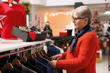 Son sınıf öğrencisi bayram kıyafetleri ve aksesuar dükkanında hediyeler ve Noel yemeği kıyafetleri arıyor. Alışveriş merkezinde kadın kumaşları kontrol ediyor..