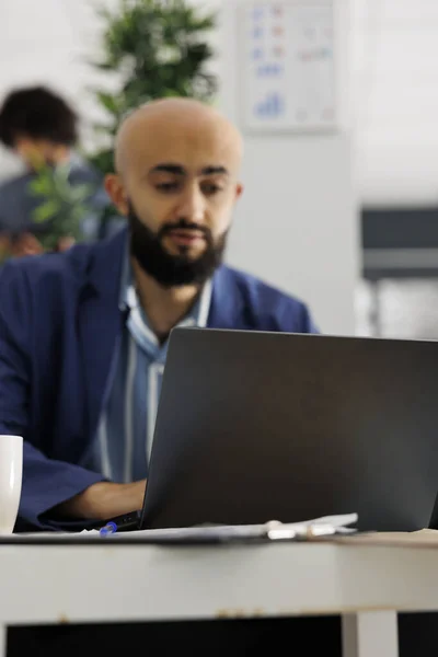 公司创业者在办公室的笔记本电脑上工作的同时 正在准备产品发布策略 阿拉伯商人计划在共同工作空间的工作场所对计算机进行营销研究 — 图库照片