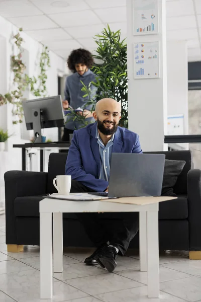 微笑成功的Arab商人在笔记本电脑上工作的合作空间肖像 快乐自信的独角兽商人坐在办公室的沙发上 看着相机 — 图库照片