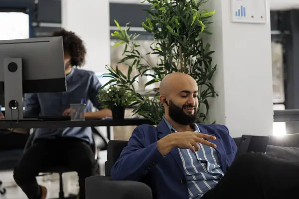 在使用数字平板电脑的视频通话中 与客户端启动Ceo对话 年轻的阿拉伯商人坐在商务合作空间的沙发上参加在线会议 — 图库照片