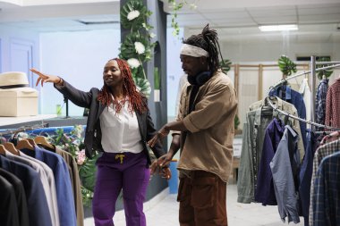 Kaygısız Afrikalı Amerikalı çift dans ediyor ve mağazada kıyafet seçiyorlar. Arkadaşlar alışveriş merkezinde müzik dinliyor ve satılık kıyafetlerle dolu rafların yanında dururken hareketler yapıyorlar.
