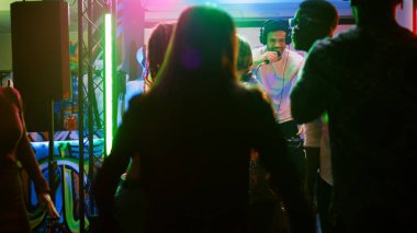 Gençler gece kulübünde eğleniyorlar. Elektronik müzikle dans ediyorlar. Disko partisinin keyfini çıkarıyorlar. Kulüpte dans eden arkadaşlar, diskotekte neşeli hissediyorlar. El kamerasıyla..