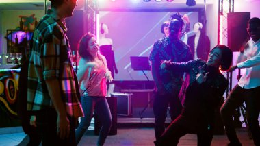 Neşeli yetişkinler disko partisinde dans ediyor, dans pistinde sosyal buluşmada eğleniyorlar. Modern funky insanlar gece kulübünde canlı müzik eşliğinde dans figürleri sergiliyorlar. El kamerasıyla..
