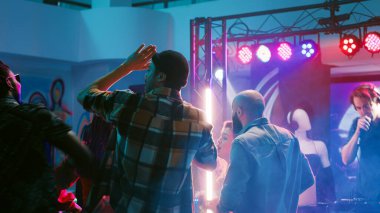 Disko müziğinde dans eden, spot ışıklarıyla eğlenen ve diskotekte dans eden gençler. Neşeli insanlar, arkadaşlarıyla sosyal toplantının keyfini çıkarıyorlar ve sahnede gösteri yapıyorlar. Üçayak atışı.