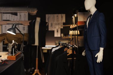 Üstün kaliteli giysi koleksiyonu ve duvarlarda moda tasarımı çizimleriyle dolu zarif profesyonel terzilik stüdyosu. Mankenler üzerindeki şık kıyafetlerle daha iyi bir dükkan.