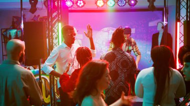 Çeşitli insanlar sahnede DJ 'le parti yapıyor, genç adam dans pistinde kalabalığın sesi için elektronik sesleri karıştırıyor. Arkadaşlar dans ediyor ve yeraltı disko partisinde eğleniyorlar. El kamerasıyla..