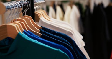 Renkli gömleklerle dolu askıların seçici odak noktası, modaya uygun kıyafetlerle dolu boş modern butik dosyalar. Alışveriş merkezinde günlük ve resmi kıyafetlerle donatılmış giyim mağazası. Moda konsepti