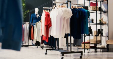 Alışveriş merkezinde boş modern butik, raflarda yeni moda koleksiyonu. Askılarda şık kıyafetler, giyim mağazası müşterilere indirimli ürünler ve aksesuarlar.