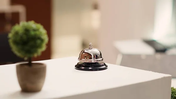 Close up of service bell next to mini plant on warm hospitality industry hotel lobby check in desk. Elegant concierge bell on modern stylish travel vacation accommodation reception counter