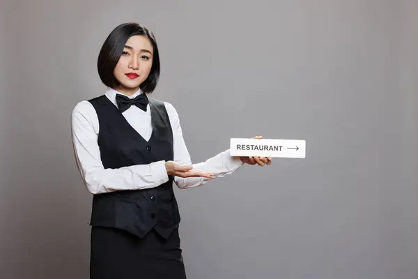 Asiatisk Servitris Håller Restaurang Riktning Skyltning Och Tittar Kameran Medan — Stockfoto