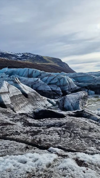 Glacier hiking vatnajokull ice cap in iceland with freezing cold icy blocks on scandinavian big lake, icelandic landscape. Majestic arctic icebergs near brown frosty hills and snowy fields.