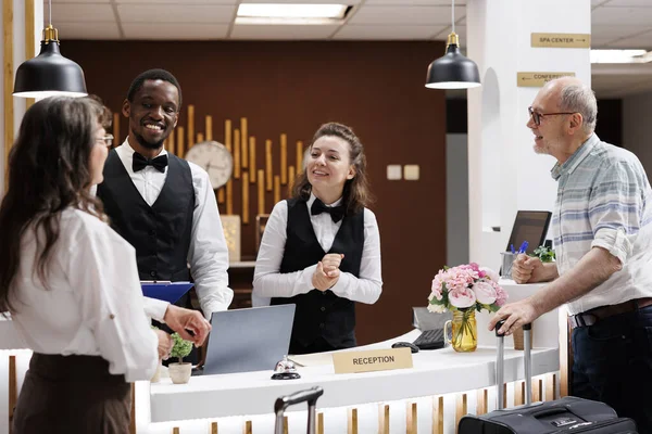 Two Elderly Tourists Arrive Suitcases Hotel Reception Check Friendly Smiling — Stock Photo, Image