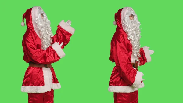 圣诞老人做广告 一边站在绿屏前一边 一边穿着节日服装 一边指指点点 男人穿得像圣人尼克 圣诞营销活动 — 图库照片
