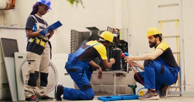 İş arkadaşı soğutucu sızıntılarını kontrol etmek ve HVC sistemindeki basıncı okumak için ölçüm cihazı kullanırken, yoğunlaştırıcı kompresör bobinlerindeki toprak ve tozun yeterli mekanik temizlik katmanı