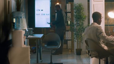 İşçi, müdürün de yardımıyla gece vardiyası sırasında bilgisayardaki istatistiksel grafikleri kontrol ederken bir fincan kahvenin keyfini çıkarıyor. Yönetimsel denetim altında çalışan muhasebeci