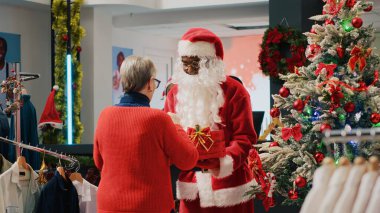 Xmas giyim mağazasındaki müşteriler Noel Baba kılığındaki işçilere çekiliş bileti veriyor. Kış tatili organizasyon çalışanı tanıtım etkinliği