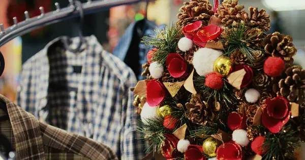 空のショッピング モール ストアの服棚からぶら下がっている松のコーンで飾られたお祝いのクリスマス リースのドリーのショットは 冬の休日のシーズン中に陽気を持って来る準備ができて 閉じます — ストック写真