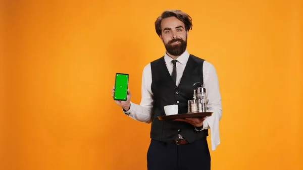 Brodaty Kelner Prezentuje Zielony Ekran Wyświetlaczu Telefonu Trzymając Smartfona Aby — Zdjęcie stockowe