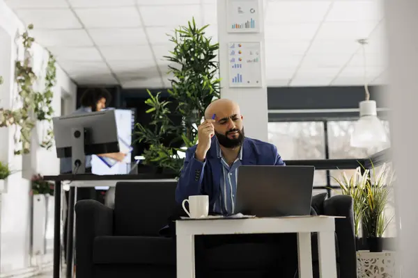 专心致志的阿拉伯人在创业办公室的笔记本电脑上工作的同时 还在思考项目财务报告 公司员工在解决营销问题的同时擦头 — 图库照片