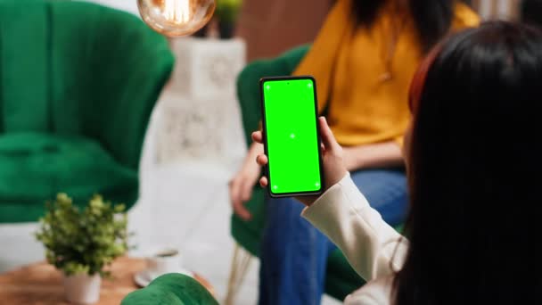 スマートフォンのレイアウトで緑色のディスプレイをチェックし ホテルでラウンジエリアで時間を過ごす女性 スクリーン上で隔離された染色体テンプレートを実行している携帯電話でソファに座っているアジアの観光客 — ストック動画