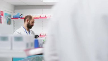 Sağlık personeli eczane raflarındaki tüm eczaneleri düzenliyor, reçeteli ilaç veya eczane tezgahındaki vitaminleri düzenliyor. Tıbbi ürünleri sayıp tarayan iki çalışan..