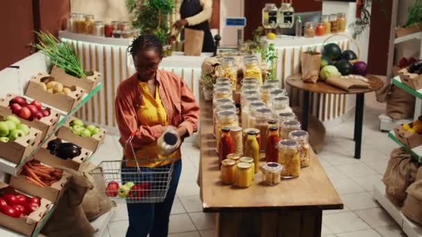 非洲裔美国人买家把意大利面和有机酱汁放进篮子里 选择纯伦理道德的食物替代品 妇女从当地杂货店购买无害生态的天然产品 摄像头B — 图库视频影像
