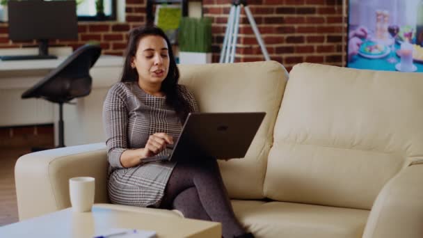 현대적인 세련된 아파트 거실에서 휴식을 취하면서 온라인 친구들과 노트북을 비디오 — 비디오