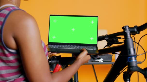 机械师在工作室后台工作室做自行车维修 查看绿色屏幕笔记本电脑维护列表 彩色按键笔记本电脑上替换自行车零件的专家在线检查 — 图库视频影像