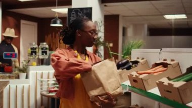 Alışverişci marketten taze sebze seçiyor, sağlıklı besleniyor ve yerel sıfır atık eczanesinden ürün satın alıyor. Afrikalı Amerikalı müşteriler organik gıda alışverişi yapıyor. Kamera B.