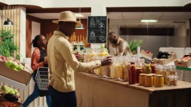 Afrika kökenli Amerikalı alıcı organik ürünler ve ev yapımı kirletici olmayan kiler almak için yerel çiftçi pazarını ziyaret ediyor. Tekrar kullanılabilir kavanozlarda toplu ürünler almak için sepet taşıyan bir müşteri. Kamera B.