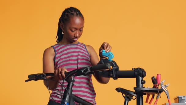 非裔美国妇女建立自行车修理站 用它来调整脱轨 修理破碎的车轮 工作室背景 专业地把自行车放在工作台上检查 相机A — 图库视频影像
