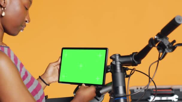 机械师在工作室后台工作室做自行车维修 查看孤立的屏幕平板电脑维护列表 模拟电子设备上替换自行车零件的在线专家检查 — 图库视频影像