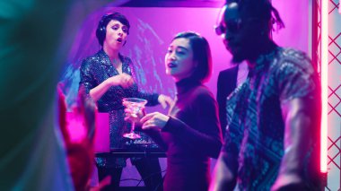 Havalı bir kadın DJ 'in partide sahnede müziği karıştırması, ses panel istasyonunda bir grup insanla dans etmesi. Genç insan arkadaşlarıyla eğleniyor, diskotekte eğleniyor..